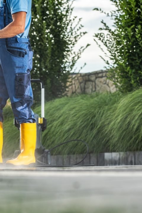 Caucasian Garden Worker Pressure Washing Residential Driveway Using Modern Pressure Washer Worker Pressure Washing Residential Driveway Using Modern Pressure Washer
